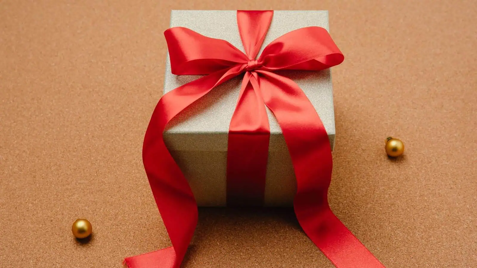 رابط أنيق هدية مغلفة برباط أحمر على خلفية ذهبية لعلامة كادو مصر.